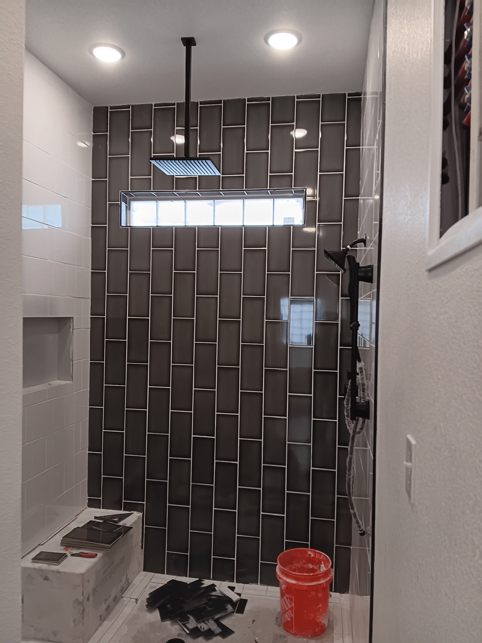 Modern shower with dark subway tile walls, glass enclosure, and recessed lighting