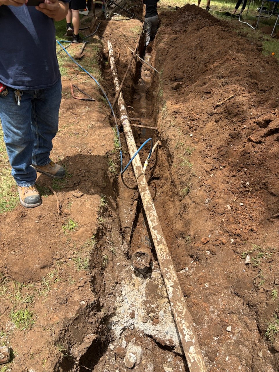 Underground sewer line installation with concrete pipe in excavated trench