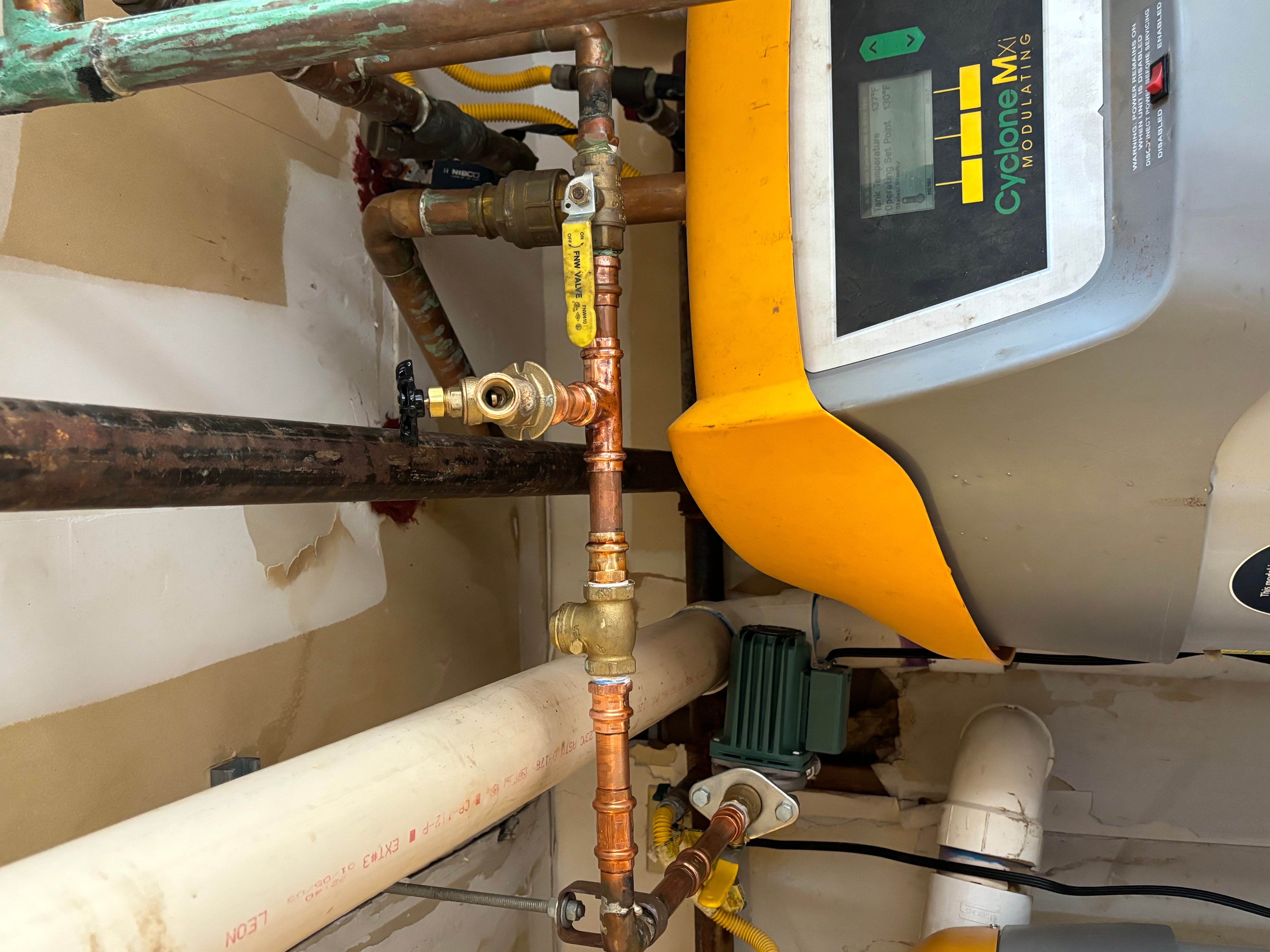 Tankless water heater installation with copper piping and control panel in utility space
