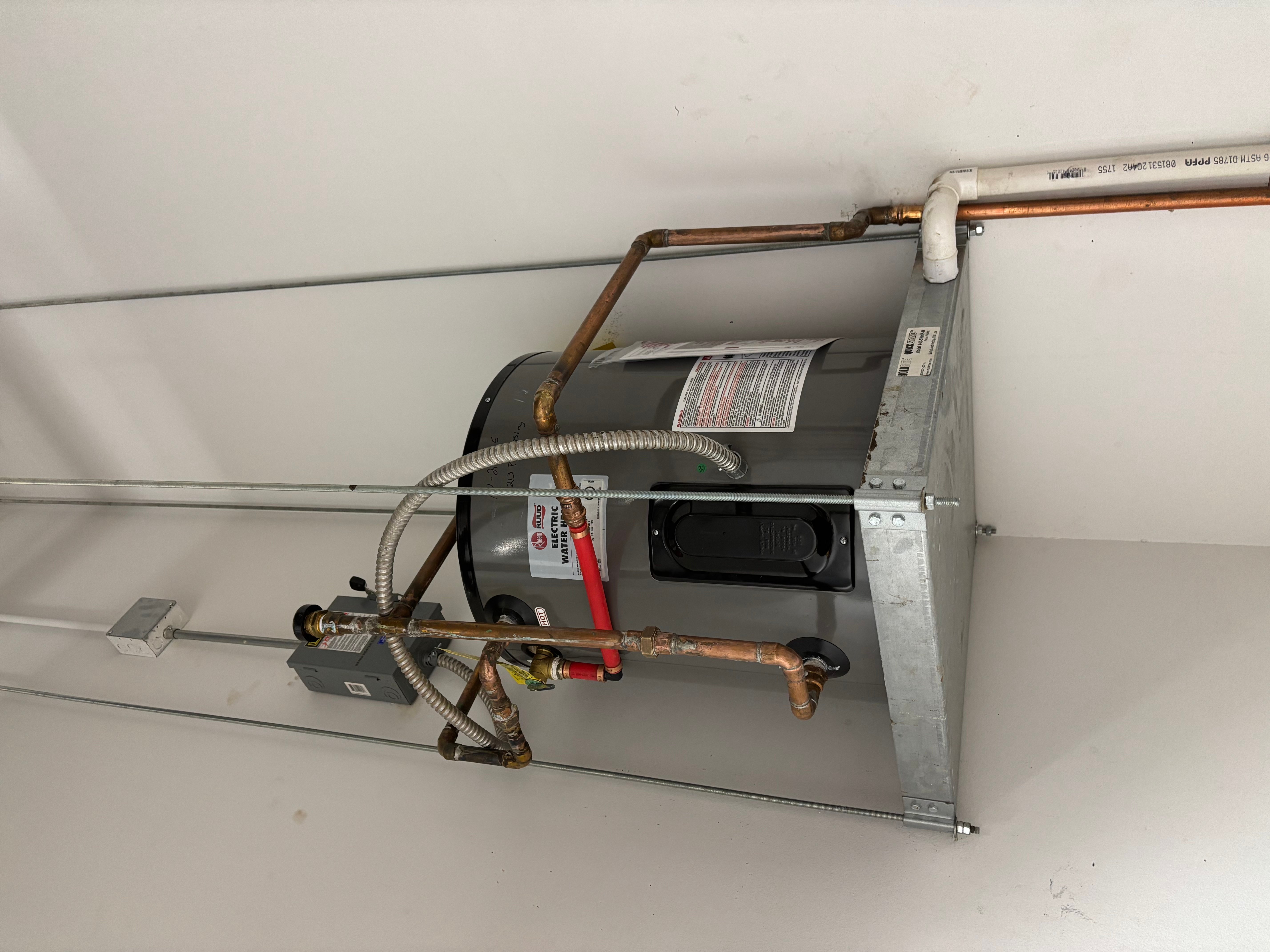 Installed electric water heater with copper piping and PVC vent connections