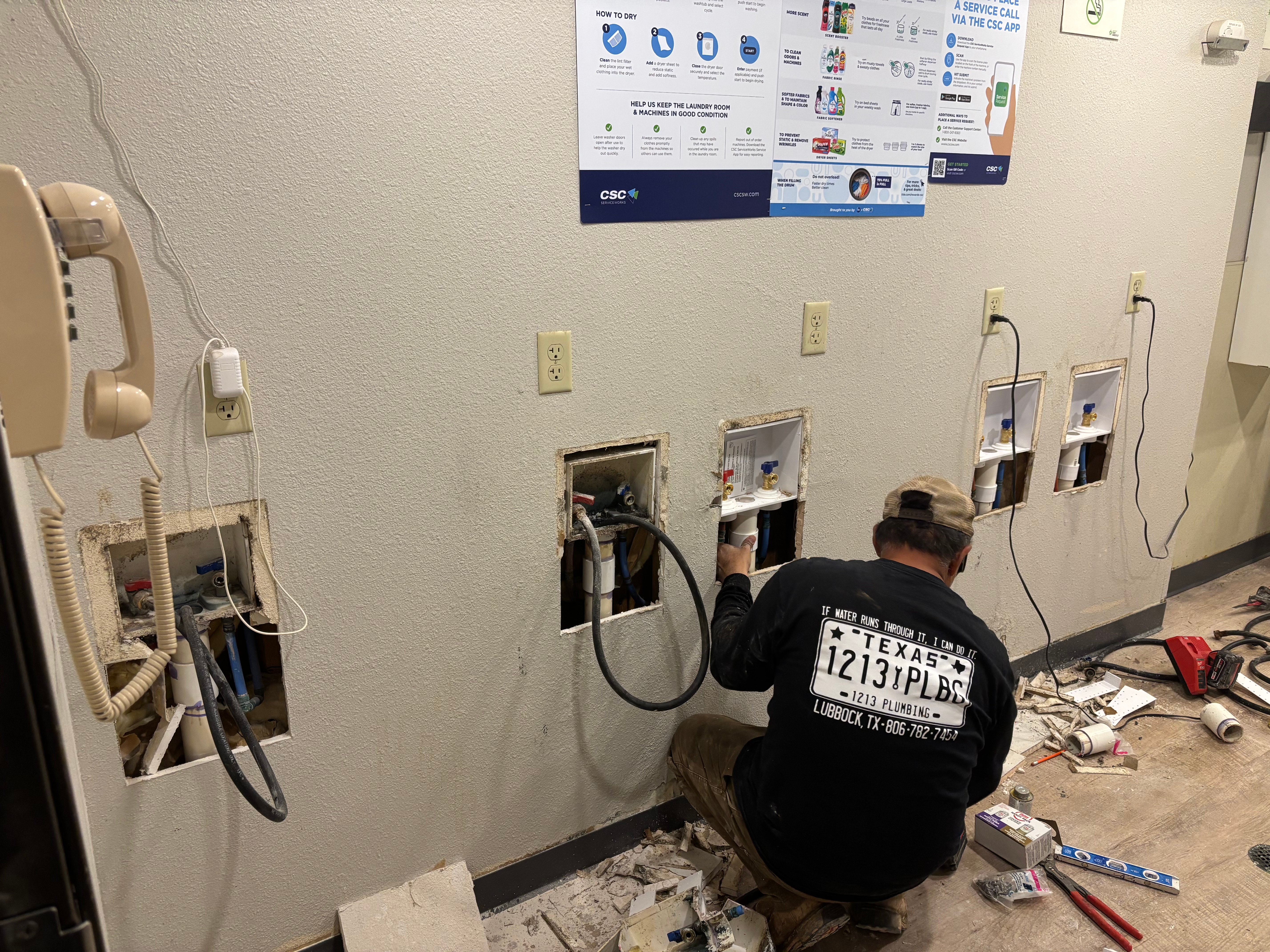 Plumber installing electrical outlets and plumbing rough-in on drywall