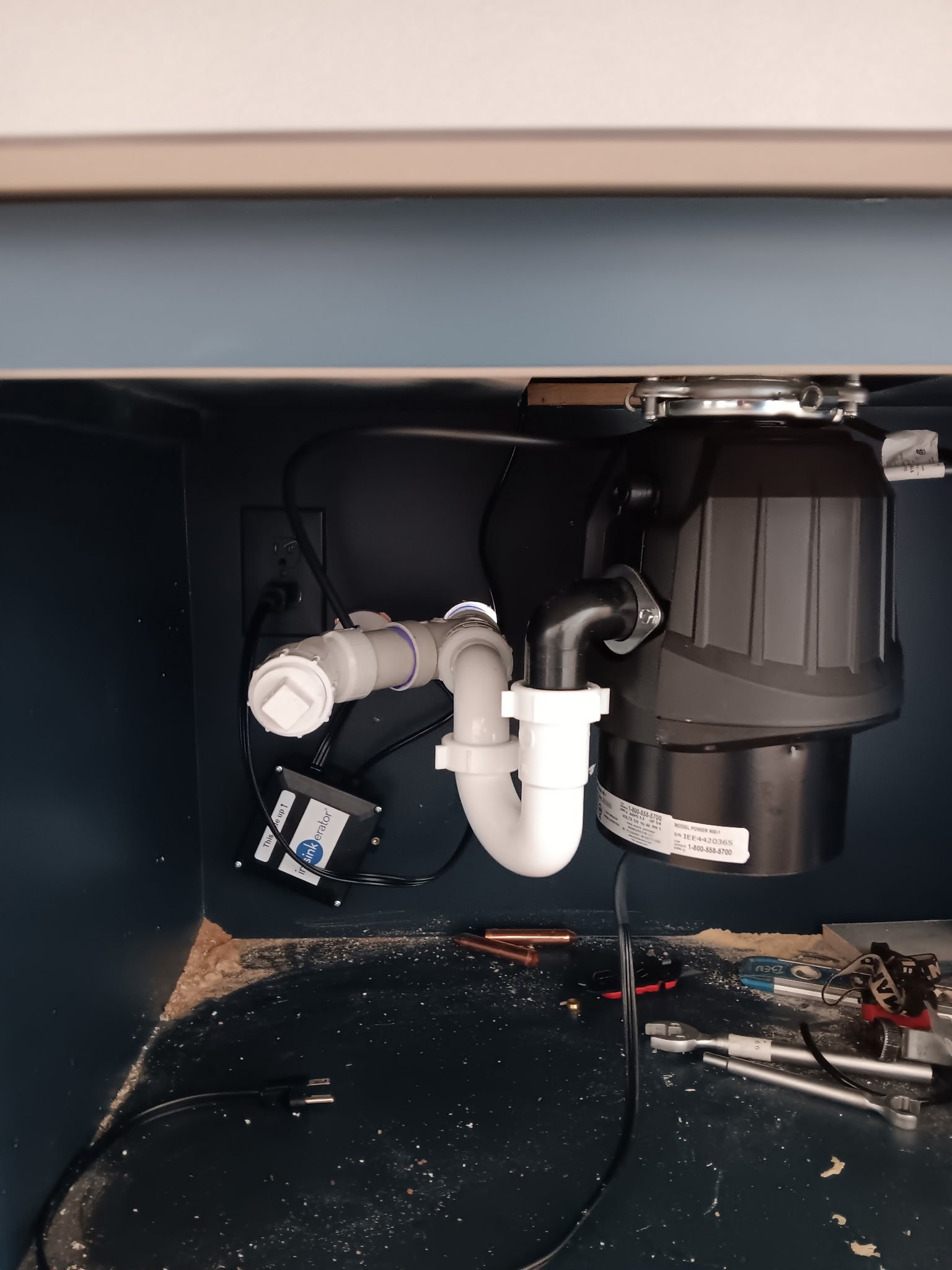 Under-sink plumbing with P-trap, garbage disposal, and supply lines installed in cabinet