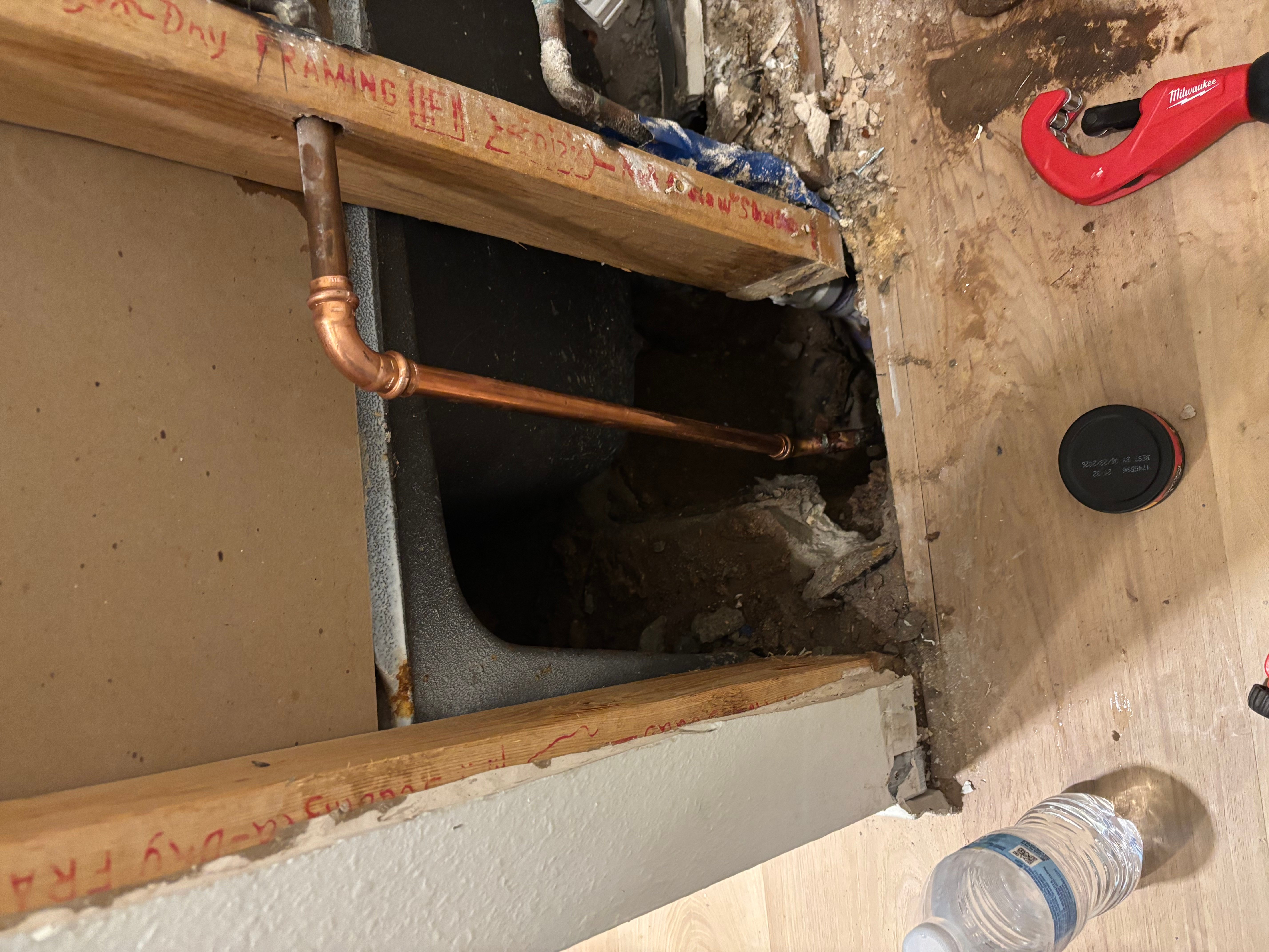 Copper water pipes with elbow fittings installed through framed wall opening