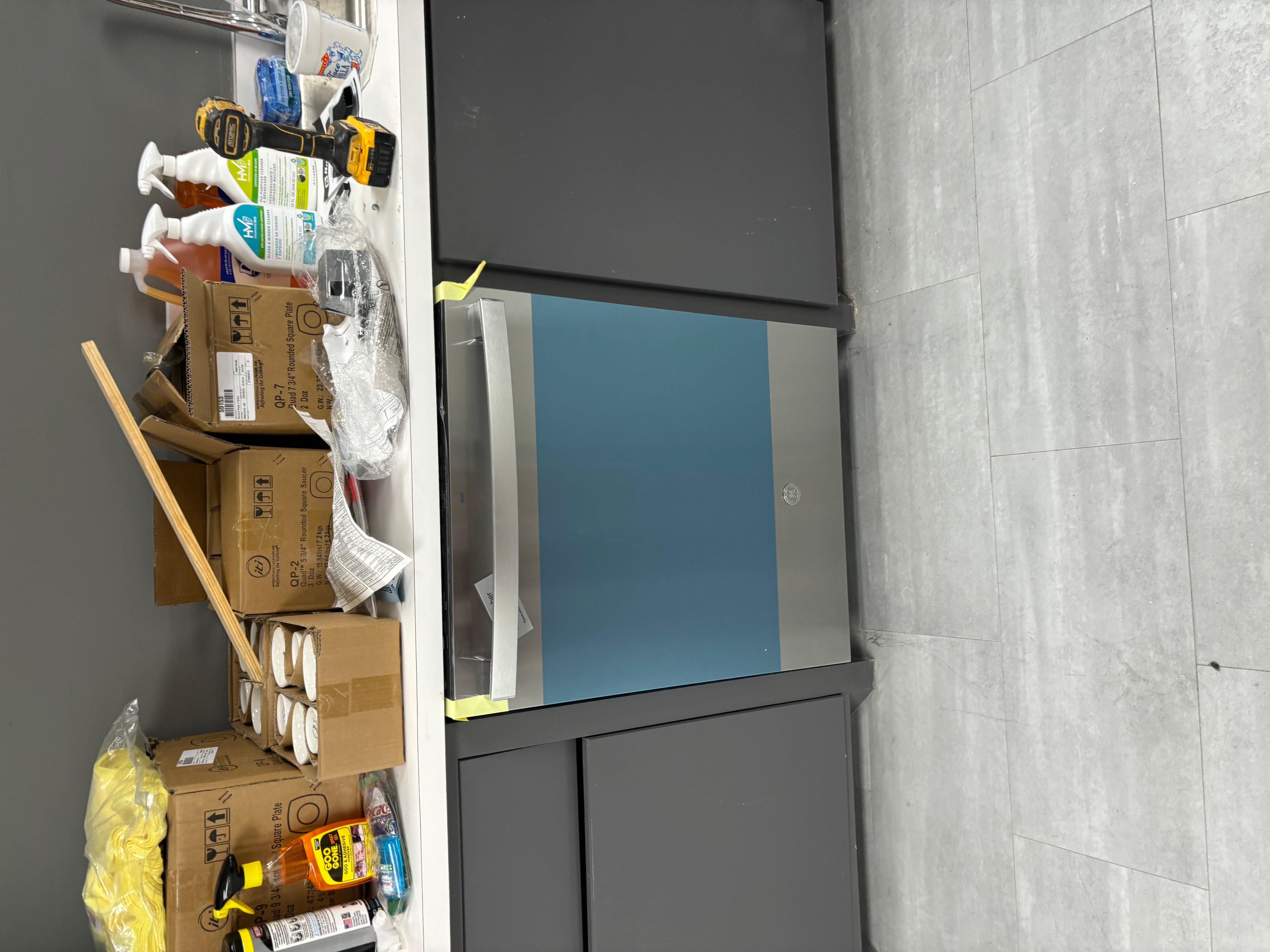 Gray tile bathroom with blue accent panel and plumbing fixture installation in progress