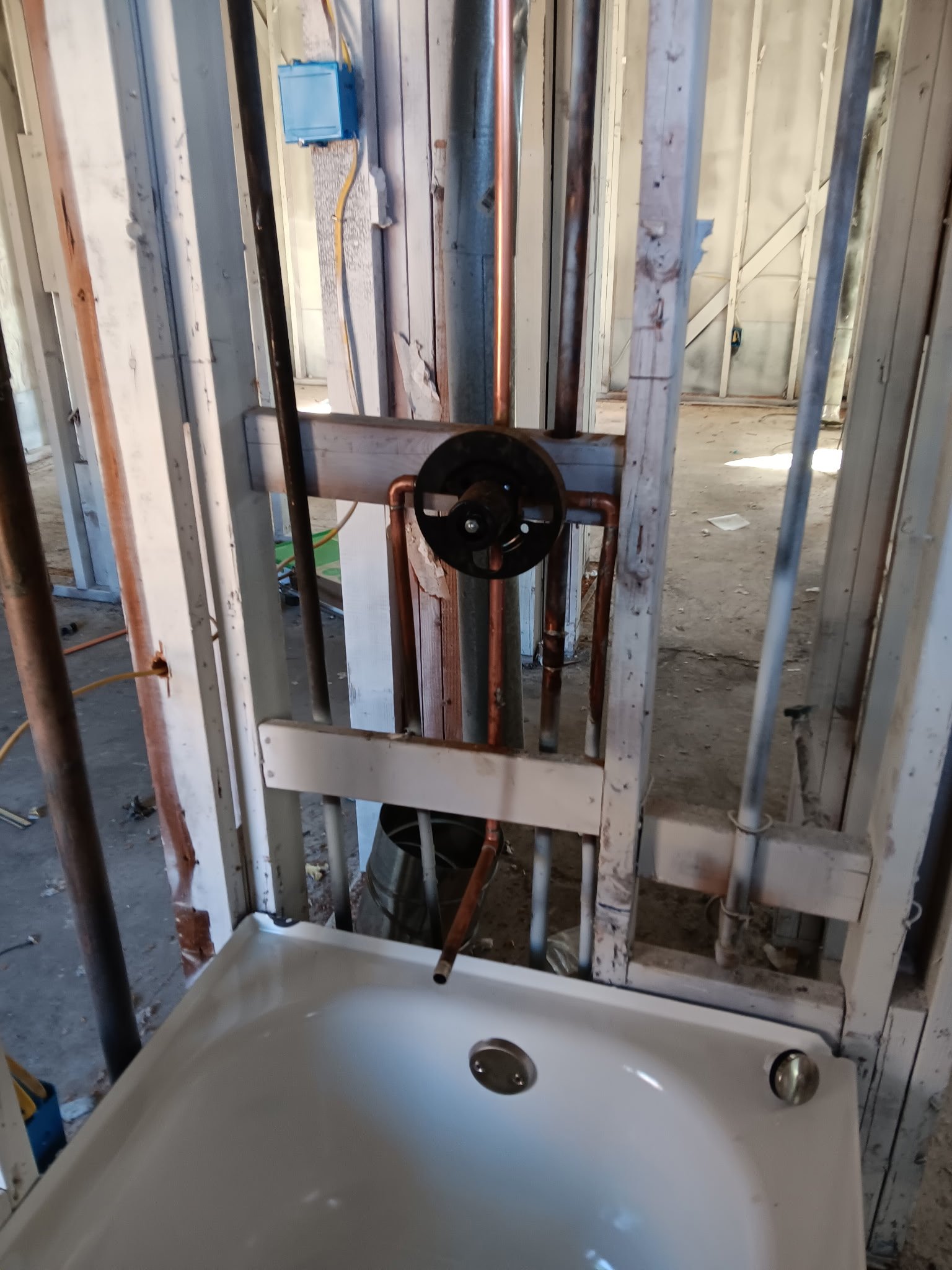 Bathroom rough-in plumbing with copper lines, drain pipes, and white sink basin during installation